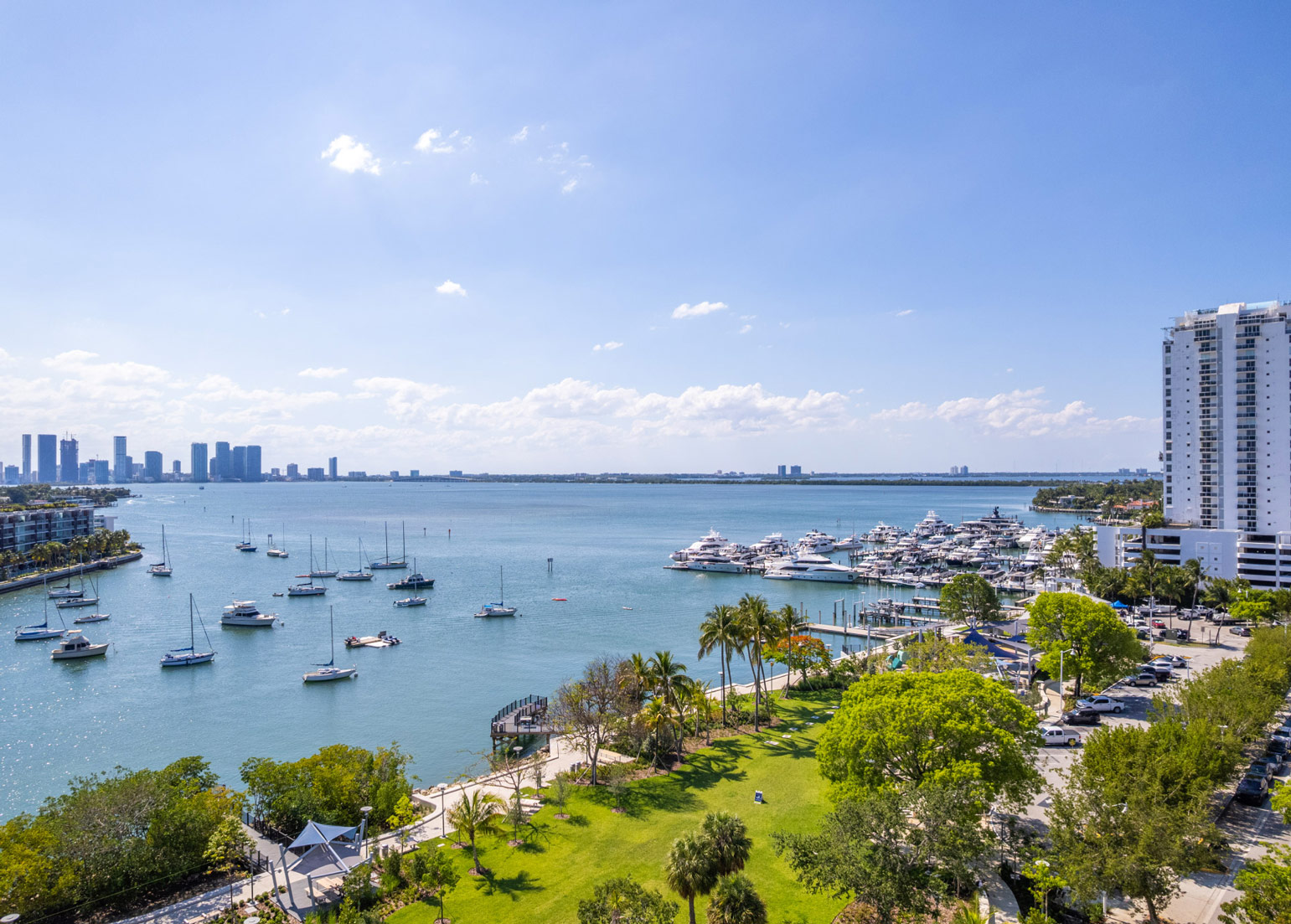Waterfront view in Miami Beach, FL, with sailboats, a marina, & green park space